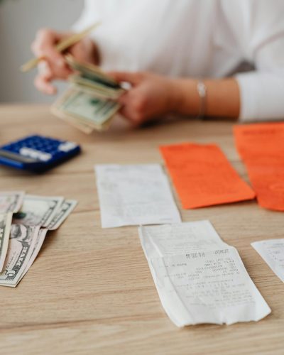 Une personne utilisant une calculatrice et de l'argent pour planifier un budget familial.