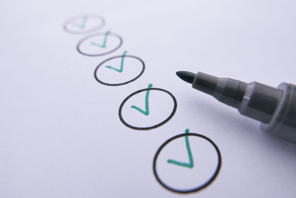 Close-up of a checklist with green checkmarks on white paper using a marker. Gros plan d'une liste de contrôle avec des coches vertes sur du papier blanc à l'aide d'un marqueur.