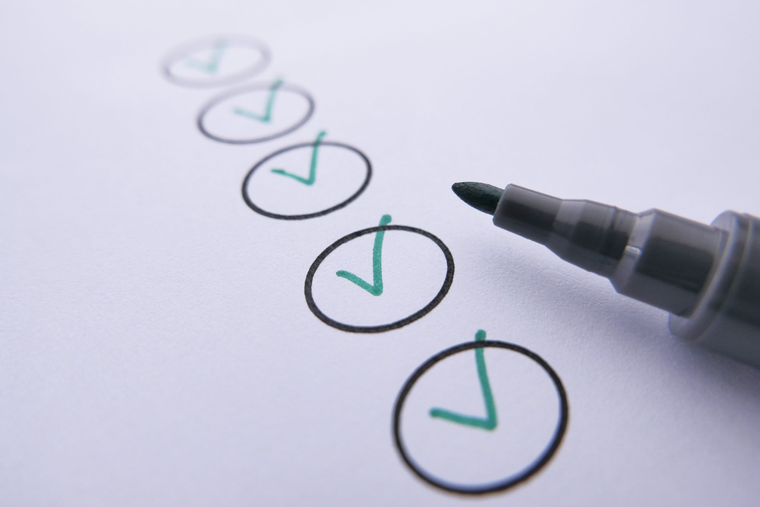 Close-up of a checklist with green checkmarks on white paper using a marker. Gros plan d'une liste de contrôle avec des coches vertes sur du papier blanc à l'aide d'un marqueur.