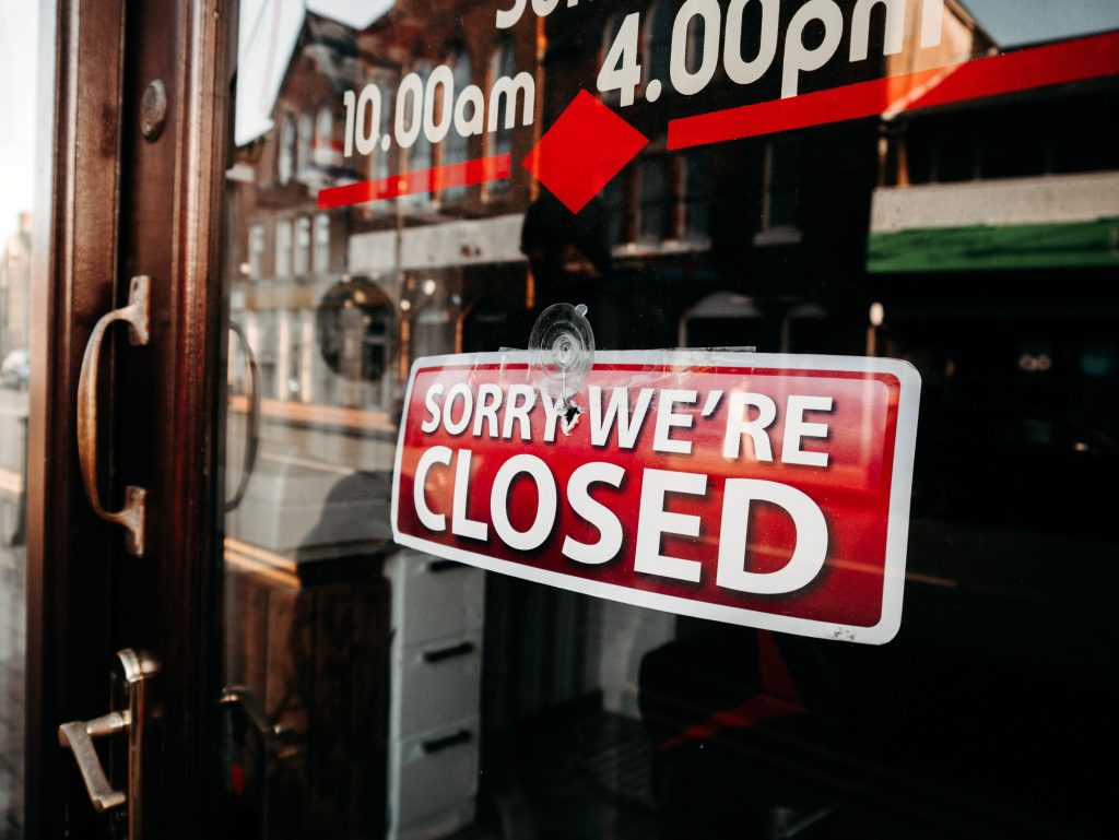 Close-up of a shop's closed sign on a glass door reflecting the street outside. Gros plan d'une pancarte fermée d'un magasin sur une porte vitrée reflétant la rue dehors.