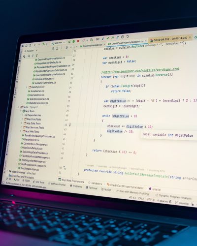 A laptop screen showing a code editor with visible programming code in a dimly lit environment. Un écran d'ordinateur portable affichant un éditeur de code avec du code de programmation visible dans un environnement faiblement éclairé.