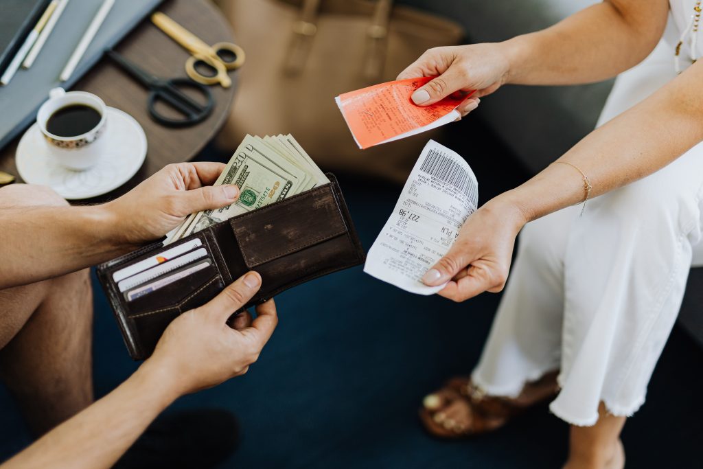 Close-up of a financial transaction involving cash and receipts over a coffee table. Gros plan d'une transaction financière impliquant de l'argent liquide et des reçus sur une table basse.