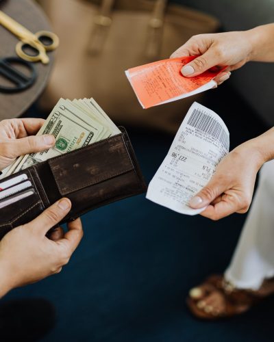Close-up of a financial transaction involving cash and receipts over a coffee table. Gros plan d'une transaction financière impliquant de l'argent liquide et des reçus sur une table basse.