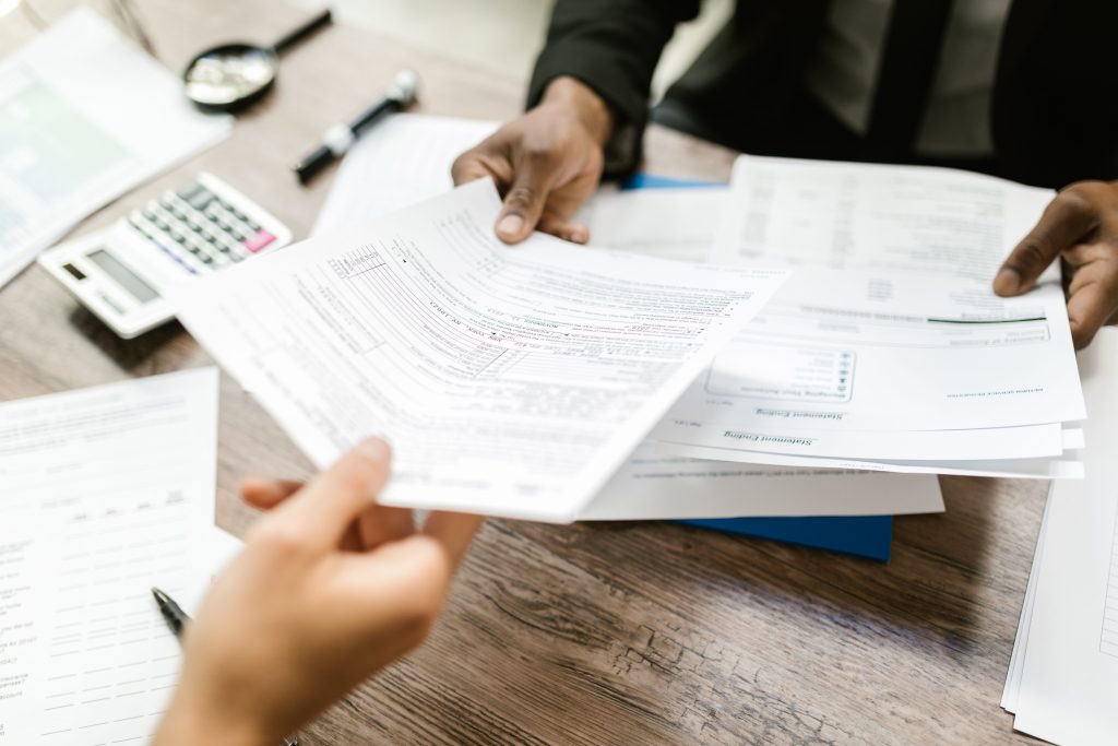 Two professionals exchanging documents in an office setting, focusing on paperwork and data analysis. Deux professionnels échangeant des documents dans un cadre de bureau, en se concentrant sur le travail administratif et l'analyse de données.