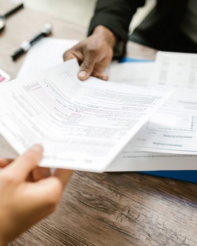 Two professionals exchanging documents in an office setting, focusing on paperwork and data analysis. Deux professionnels échangeant des documents dans un cadre de bureau, en se concentrant sur le travail administratif et l'analyse de données.