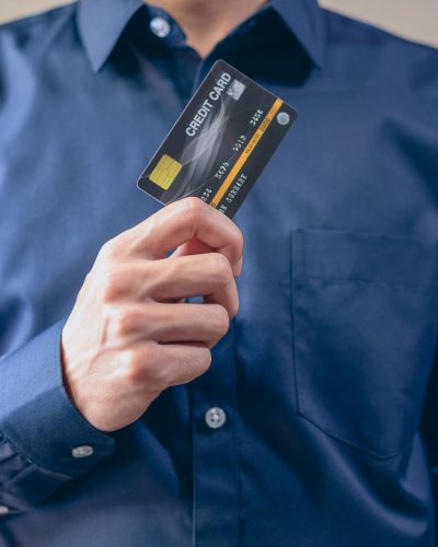 Close-up of a man in a blue shirt holding a credit card, symbolizing finance and security. Gros plan d'un homme en chemise bleue tenant une carte de crédit, symbolisant la finance et la sécurité.