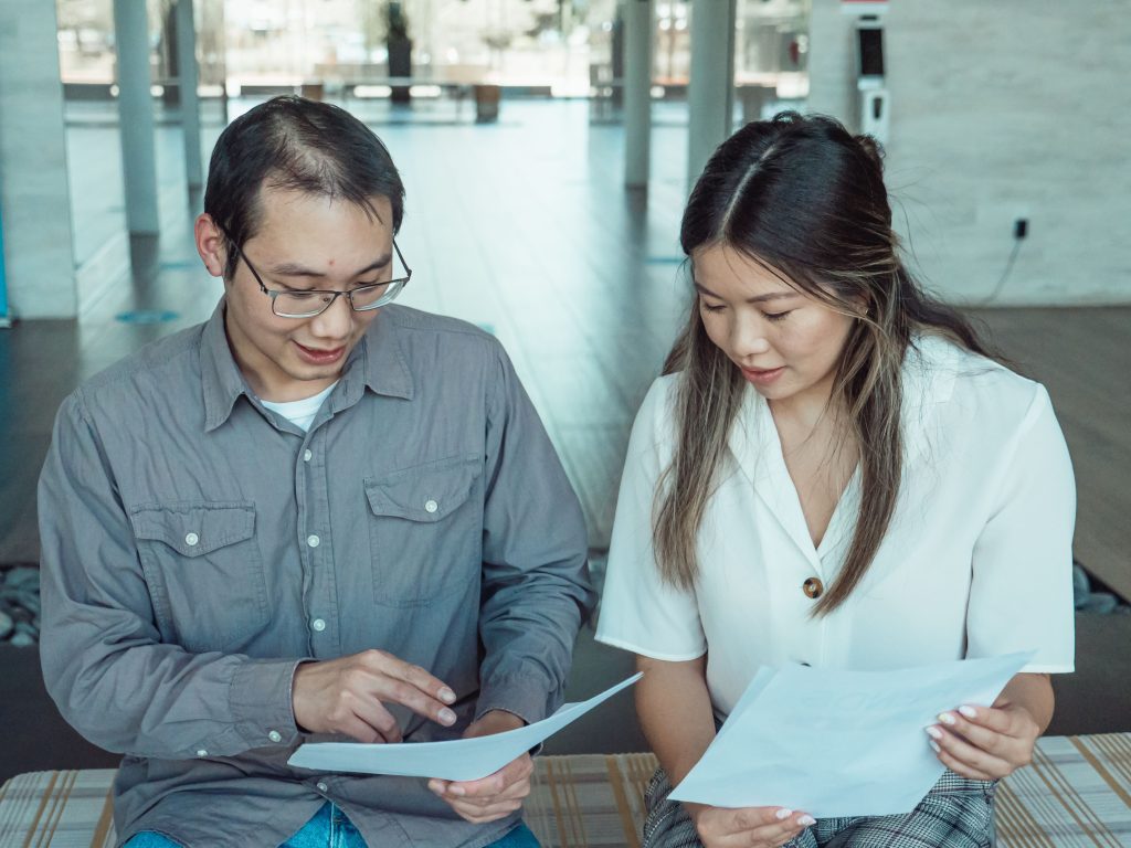 Two coworkers reviewing documents in a modern office, focused on teamwork and planning. Deux collègues examinant des documents dans un bureau moderne, axés sur le travail d'équipe et la planification.