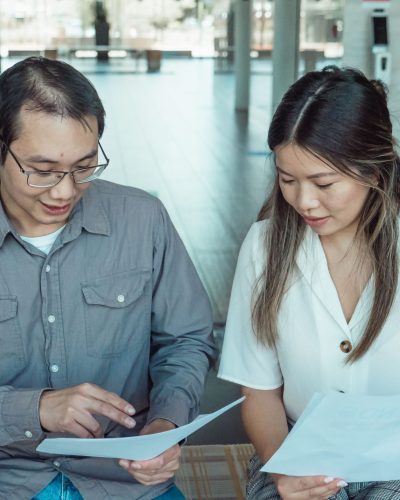 Two coworkers reviewing documents in a modern office, focused on teamwork and planning. Deux collègues examinant des documents dans un bureau moderne, axés sur le travail d'équipe et la planification.
