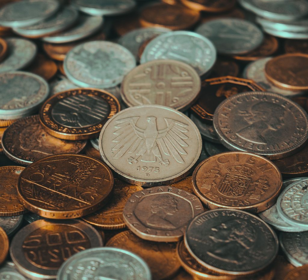 Close-up of various international coins, showcasing diverse currency designs and historical significance. Gros plan sur diverses pièces de monnaie internationales, mettant en évidence des designs de devises diversifiés et leur importance historique.