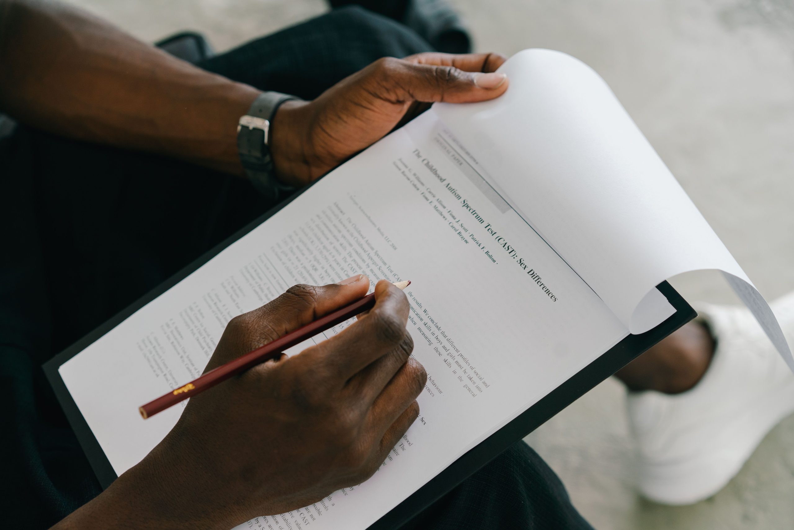 Close-up of a person writing on a psychological assessment form with a pencil. Gros plan d'une personne écrivant sur un formulaire d'évaluation psychologique avec un crayon.