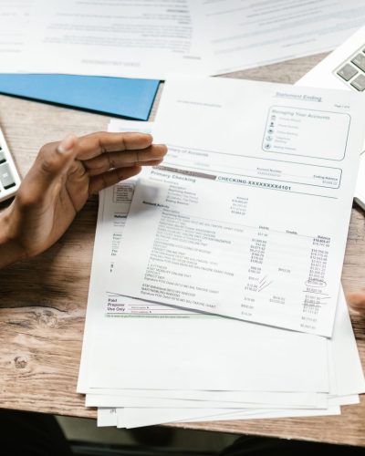 Hands holding financial documents with calculator and laptop on office desk, business analysis scene. Des mains tenant des documents financiers avec calculatrice et ordinateur portable sur un bureau de bureau, scène d'analyse commerciale.