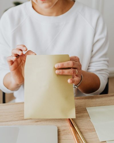 Femme qui scelle une enveloppe sur un bureau en bois